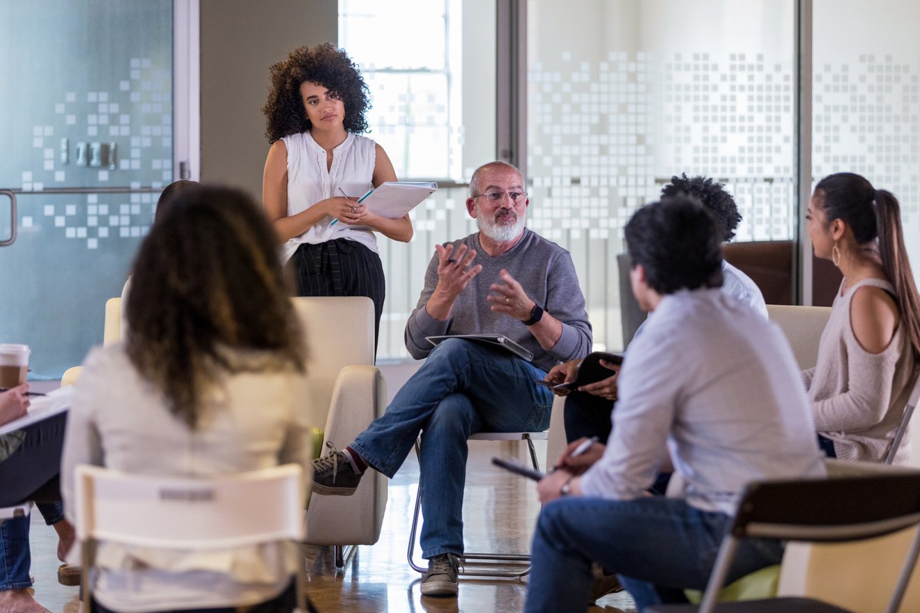 Diverse group of employees meet casually with senior management